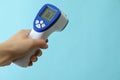 Female hand hold thermometer gun on blue background Royalty Free Stock Photo