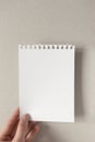 Female hand hold torn white empty blank notebook paper page with copy space on gray background. Vertical Royalty Free Stock Photo