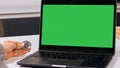 Female hand holding a bitcoin next to the laptop with a green screen
