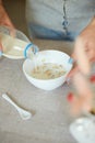 Female hand holding bottle pouring milk in cereal granola flakes bowl Royalty Free Stock Photo