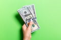 Female hand holding a bundle of money on colorful background. Top view of one hundred dollar banknotes. Salary concept