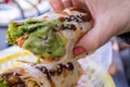 Female hand holding a burrito covered with guacamole