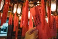 Hand holding a card with prayers hanging from a lantern in the Man Mo Temple in Hong Kong