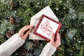 Female hand holding a Christmas card on background of Christmas fir branches, spruce, juniper, fir, larch