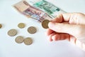 Female hand holding a coin, coins and russian rubles on the table Royalty Free Stock Photo