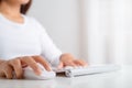 Female hand holding computer wireless mouse and working on a computer keyboard. work at home concept Royalty Free Stock Photo