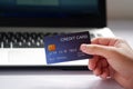 Female hand holding credit card and laptop computer on white desk. Concept of Online shopping and payment Royalty Free Stock Photo