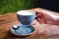 Female hand holding a cup of cappuccino coffee with milk foam in a summer cafe, close up Royalty Free Stock Photo