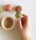 Female hand are holding a cup of coffee with macarons. White backgrounds . Flat lay, top view.