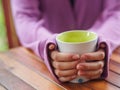 Female hand holding a cup on wooden table. Royalty Free Stock Photo