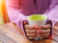 Female hand holding a cup on wooden table. Royalty Free Stock Photo