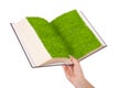 Female hand holding a ecological book with grass on white background