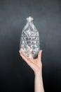 Female hand holding empty crushed plastic bottle isolated on black background. Recyclable waste. Recycling, reuse, garbage disposa Royalty Free Stock Photo