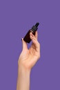 Female hand holding essential oil bottle on purple background. Female hand with glitter red manicure. Essential parfume bottle Royalty Free Stock Photo