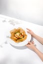 Female hand holding fish dish. Roasted fish in hand of person. Food menu with hand. Person eat baked fish in white plate with Royalty Free Stock Photo