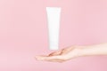 Female hand holding flacon for cream with golden cap. Plastic flacon for body lotion, toiletry. Container for cosmetics product.