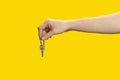 Female hand holding and giving house key on yellow background. Real estate agent Royalty Free Stock Photo