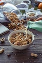 Female hand holding glass bottle pouring milk in cereal granola flakes bowl