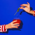 Female hand holding glass with cocktail  on bright blue neon background. Concept of taste, alcoholic drinks Royalty Free Stock Photo