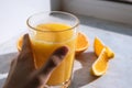 Female hand holding glass of fresh orange juice in front cut oranges on table Royalty Free Stock Photo