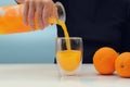 Female hand holding glass jar of fresh squeezed orange juice and pouring Royalty Free Stock Photo