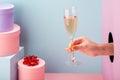 Female hand holding a glass of sparkling wine on blue and pink background Royalty Free Stock Photo