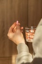 Female hand holding glass of water and pink pill. Collagen supplement for nutrition. Healthy eating lifestyle. Taking Royalty Free Stock Photo