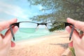 Female hand holding glasses focus mirror lens on sand sea travel