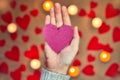 Female hand holding a glitter pink heart with romantic candle and red hearts background for Valentine`s day or romantic Royalty Free Stock Photo