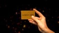 Female hand holding gold card on sparkling background, wealthy life, VIP club Royalty Free Stock Photo