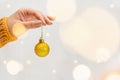 Female hand holding golden Christmas tree ball with garland bokeh on background Royalty Free Stock Photo