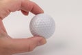 Female hand holding golf ball on light background. The white color of plastic ball is popular in the game Royalty Free Stock Photo