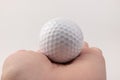 Female hand holding golf ball on light background. The white color of plastic ball is popular in the game Royalty Free Stock Photo