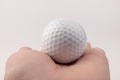 Female hand holding golf ball on light background. The white color of plastic ball is popular in the game Royalty Free Stock Photo