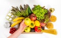 Female hand holding green apple over box with fresh fruit and vegetables, eggs, pasta and canned food. Donation or food Royalty Free Stock Photo