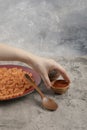 Female hand holding ground pepper and burgundy plate macaroni
