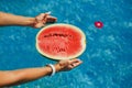 Female hand holding half of ripe juicy watermelon in the swimming pool. Freshness, Enjoyment Concept Royalty Free Stock Photo