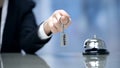 Female hand holding Hotel room keys near bell on reception, hospitality services Royalty Free Stock Photo