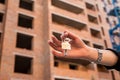 Female hand holding keys in front of a new home Royalty Free Stock Photo