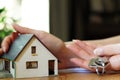 Female hand holding keys next to a miniature house - real estate business concept Royalty Free Stock Photo