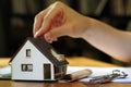 Female hand holding keys next to a miniature house - real estate business concept Royalty Free Stock Photo