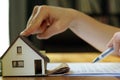 Female hand holding keys next to a miniature house - real estate business concept Royalty Free Stock Photo