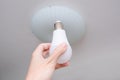 Female hand holding a led light bulb to change, replace it at home, screwing in the bulb into a lamp holder for energy saving and Royalty Free Stock Photo