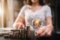 Female hand holding lightbulb with coins stack on desk. Royalty Free Stock Photo