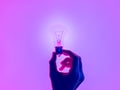 Female hand and holding luminous light bulb. Electric incandescent light bulb in hand on purple background. Inspiration Ideas conc Royalty Free Stock Photo