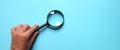 Female Hand holding Magnifying glass  on a blue backgrou Royalty Free Stock Photo