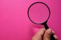 Female hand holding Magnifying glass  on a pinkbackground Royalty Free Stock Photo