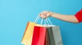 Female hand holding many colorful shopping bags on blue background Royalty Free Stock Photo