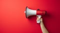 Megaphone loudspeaker in woman hands from a hole on a red wall background. Hiring, advertising. Important social choice. Royalty Free Stock Photo