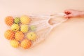 Female hand holding mesh eco bag with fruits on light background. Healthy clean eating. Eco shopping concept. Royalty Free Stock Photo